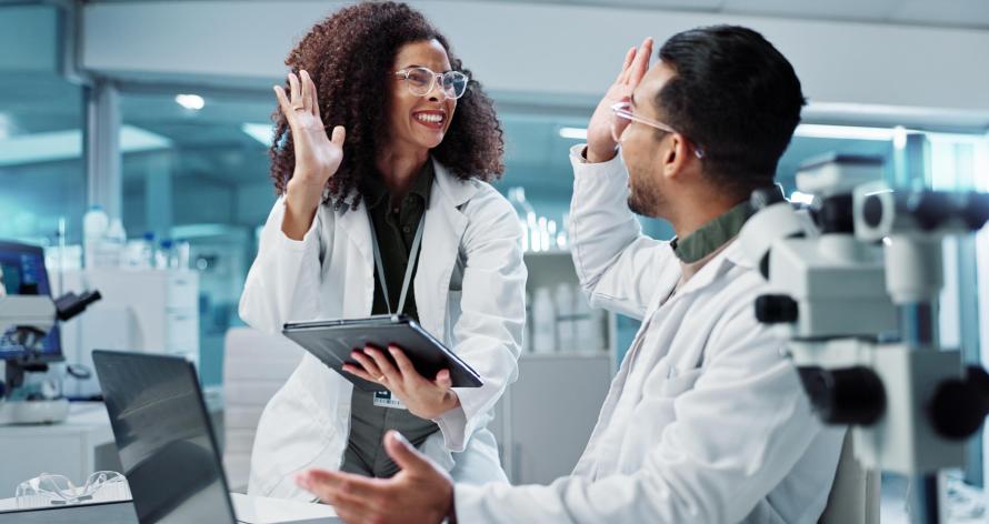 Science, teamwork and high five with laptop in laboratory for test breakthrough, pharmaceutical review or excited. Scientist, collaboration or mentor for research success, talking or digital analysis Science, teamwork and high five with laptop in laboratory for test breakthrough, pharmaceutical review or excited. Scientist, collaboration or mentor for research success, talking or digital analysis